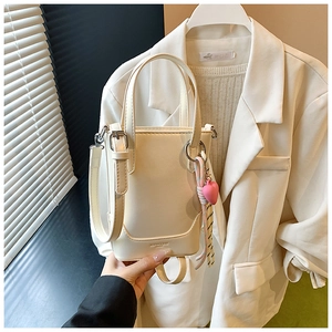Détail du sac seau crème avec texture en cuir lisse et pendentif cœur rose élégant