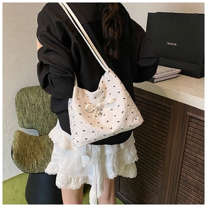 Détail du sac cabas blanc à motif nœuds noirs avec pendentif en forme de cœur argenté