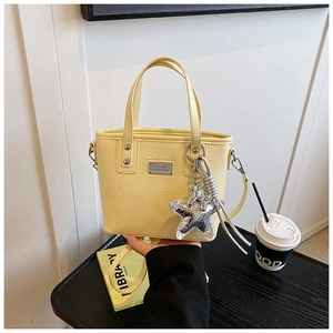 Detail of yellow crocodile pattern bucket bag with silver sequin star charm accessory