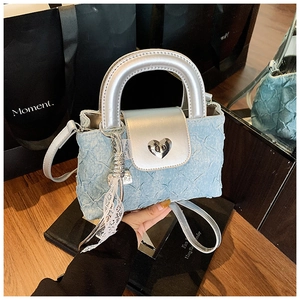 Detail of light blue denim mini bucket bag with silver leather trim and heart buckle