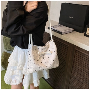 Détail du sac blanc à texture gaufrée avec imprimé nœuds noirs et pendentif cœur