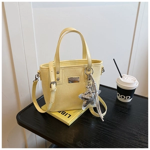 Close-up of yellow bucket bag with crocodile texture, star pendant and silver hardware