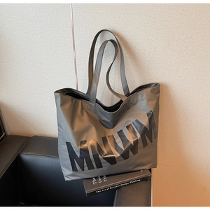 Detail of dark grey tote bag featuring large black MNWM lettering and durable shoulder straps