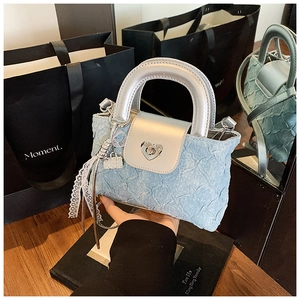 Detail of light blue denim mini bag with silver leather flap and heart-shaped metal lock