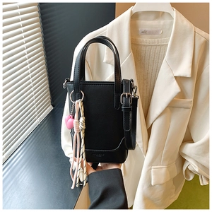 Détail du mini sac seau en cuir noir avec breloque cœur rose et poignée en corde rayée