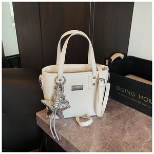 Close-up of white crocodile pattern bucket bag with silver star pendant and metal plate