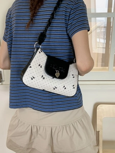 Schicke schwarz-weiße Schultertasche mit Herzanhänger und geflochtenem Riemen