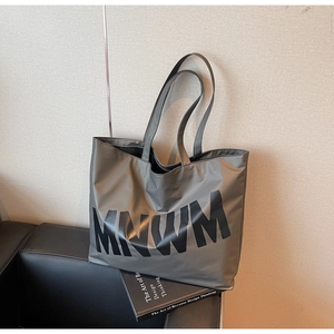 Detail of dark grey-green tote bag featuring bold MNWM lettering on smooth fabric