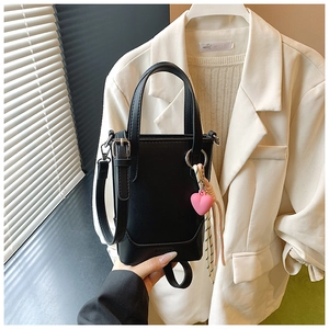 Détail du sac seau noir en cuir PU avec charm cœur rose et bandoulière amovible