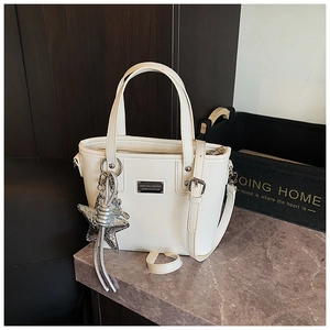 Detail of white crocodile pattern tote bag with silver star charm and long strap