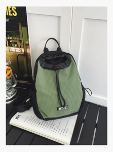 Detail des grünen karierten wasserdichten Rucksacks mit Kordelzug und MYJC-Markenlabel