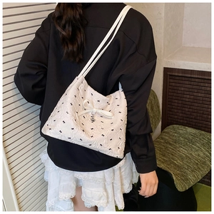 Détail du sac à bandoulière blanc plissé avec motifs nœuds noirs et pendentif cœur