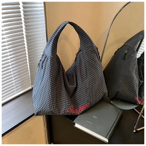 Detail of dark grey plaid hobo bag with red Our Face embroidery and wide shoulder strap