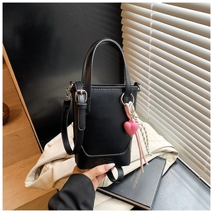 Gros plan du mini sac seau noir avec pendentif coeur et détail de foulard en soie