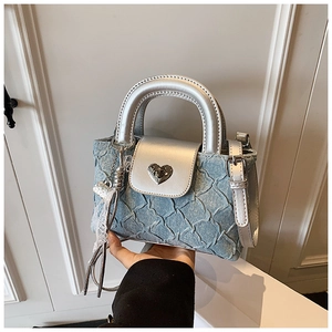 Detail of blue denim crossbody bag with silver leather trim and heart-shaped metal lock