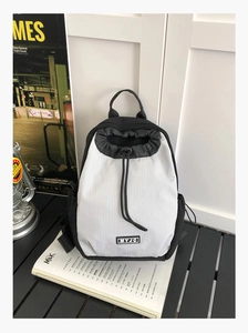 Detail des wasserdichten Mini-Rucksacks in Schwarz-Weiß-Kontrast mit praktischem Kordelzug