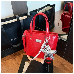 Detail of red croc-embossed bucket bag with star pendant and silver tassel charm
