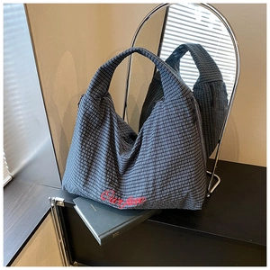 Detail of grey striped tote bag featuring red Our fave embroidery and fabric texture