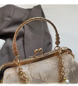 Dettaglio ravvicinato di una pochette cinese vintage con manico floreale dorato e ricamo