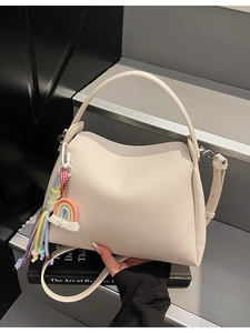 Sac seau minimaliste en cuir grainé beige avec charme pompon coloré et bandoulière