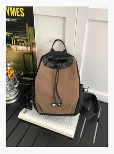 Details eines braun karierten wasserdichten Outdoor-Rucksacks mit Kordelzug und Markenlogo