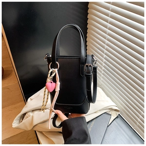 Détail du sac seau noir en cuir avec breloque cœur rose et bandoulière amovible