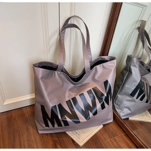 Detailed macro view of large canvas tote bag with MNWM lettering on high-quality fabric