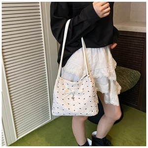 Détail du sac à bandoulière blanc avec motifs nœuds noirs et grand nœud en soie avec cœur