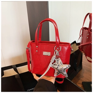 Detail view of red crocodile texture bucket bag with silver star charm and metal logo