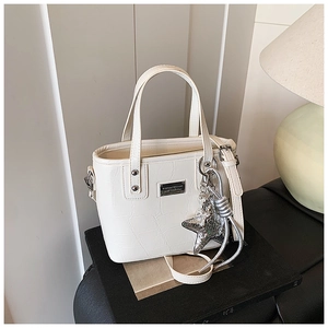 Detail of off-white crocodile embossed texture bucket bag with silver star charm