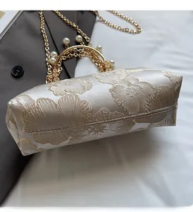 Dettaglio della borsa da sera jacquard floreale con manico di perle e nappa d'oro