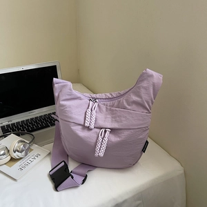 Close-up of lilac crescent crossbody bag with woven zipper pull and woven brand label