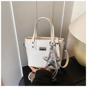 Detail of white crocodile pattern bucket bag with silver star charm and metal logo