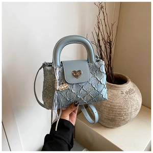 Close-up of light blue quilted denim bucket bag with silver heart-shaped twist lock