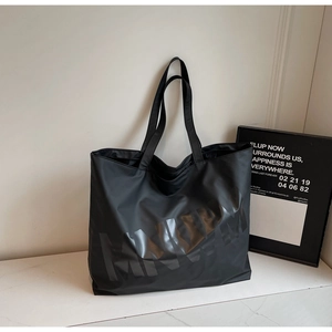 Detail of minimalist black large capacity tote bag with glossy letter print design