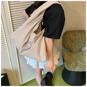 Close-up detail of beige striped tote bag with blue cursive embroidery and wide strap