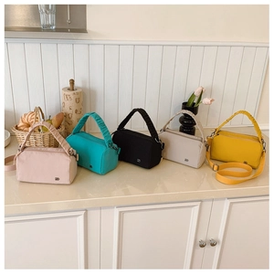 Detailed row of nylon pillow bags in pink, teal, black, and yellow with pleated handles