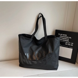 Close-up of minimalist black nylon tote bag featuring bold MINIWE logo and matte texture