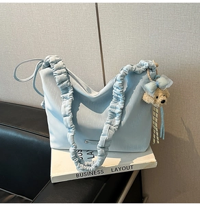 Detail of light blue tote bag with ruched cloud strap and cute bear charm pendant