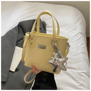 Detail of pale yellow bucket bag featuring crocodile texture and silver balloon dog charm