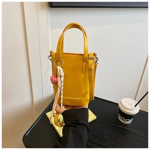 Détail du mini sac cabas jaune avec breloque cœur rose et bandoulière tressée
