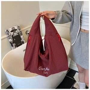 Detailed close-up of red and brown checkered quilted tote bag with white embroidery