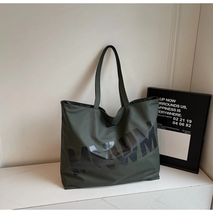 Detail of dark green large tote bag showing minimalist MNWM letter print and nylon texture