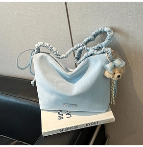 Detail of light blue tote bag with ruched strap and cute plush puppy keychain