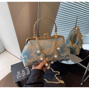 Dettaglio di ricamo floreale blu con chiusura in metallo dorato e manico di perle
