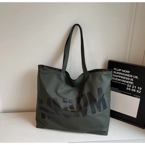 Detail of large dark olive nylon tote bag with black MNWM text on marble background