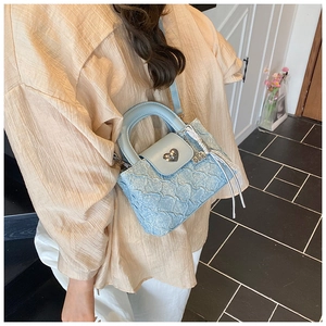 Detail of light blue quilted mini bag with silver heart clasp and ruffled texture