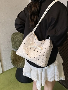 Sac fourre-tout matelassé blanc avec motifs de nœuds noirs et pendentif cœur en ruban