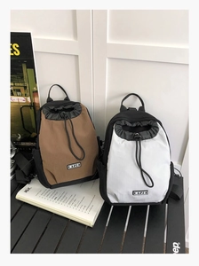 Detailansicht der zweifarbigen Mini-Kordelzug-Rucksäcke aus kariertem Nylon auf einem Tisch
