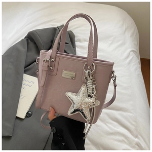 Detail showing lavender croc-embossed tote bag with silver star charm and adjustable strap